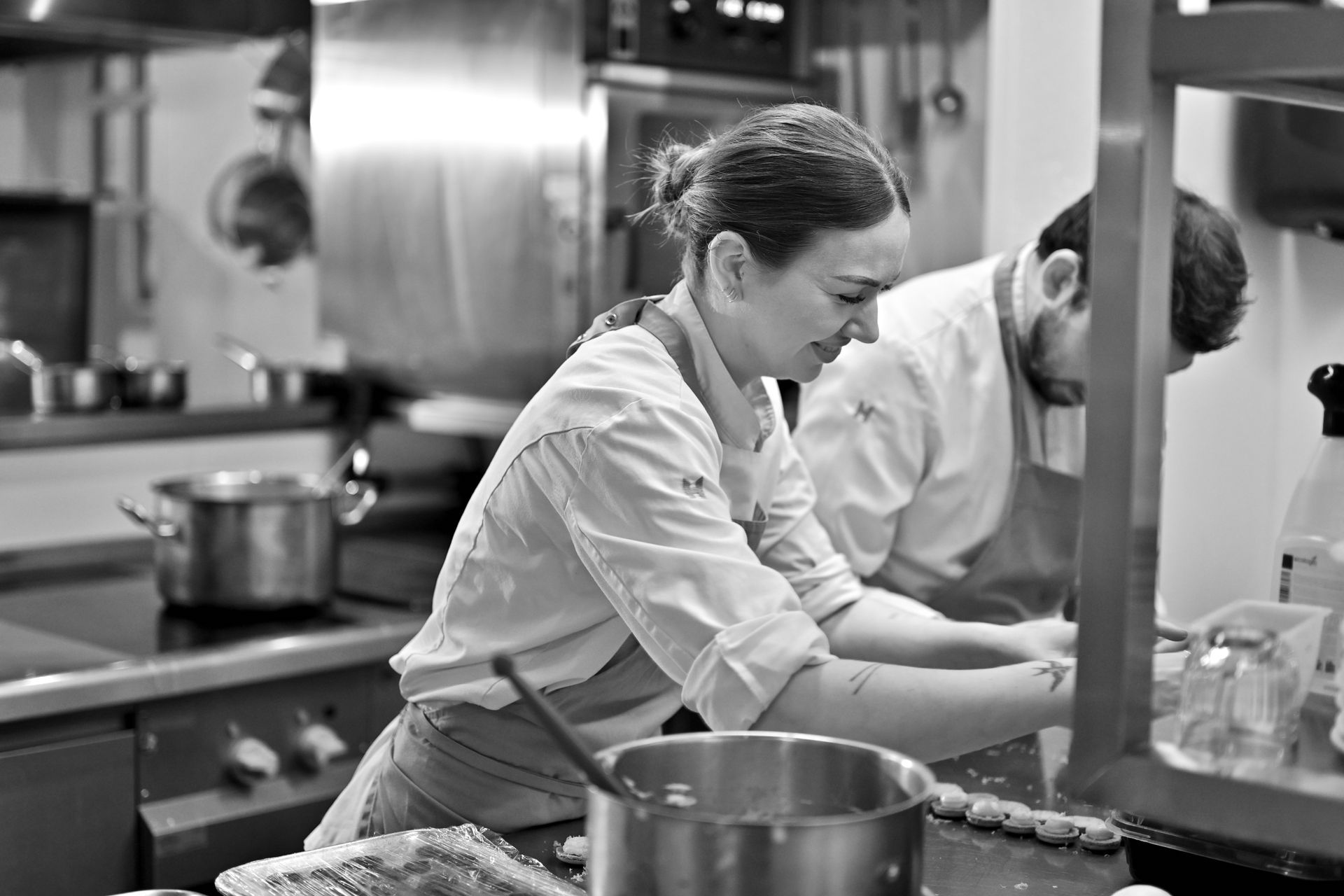 Een persoon houdt een schaal croissants vast, bij een buffet met gebak en koffie, in een keuken.