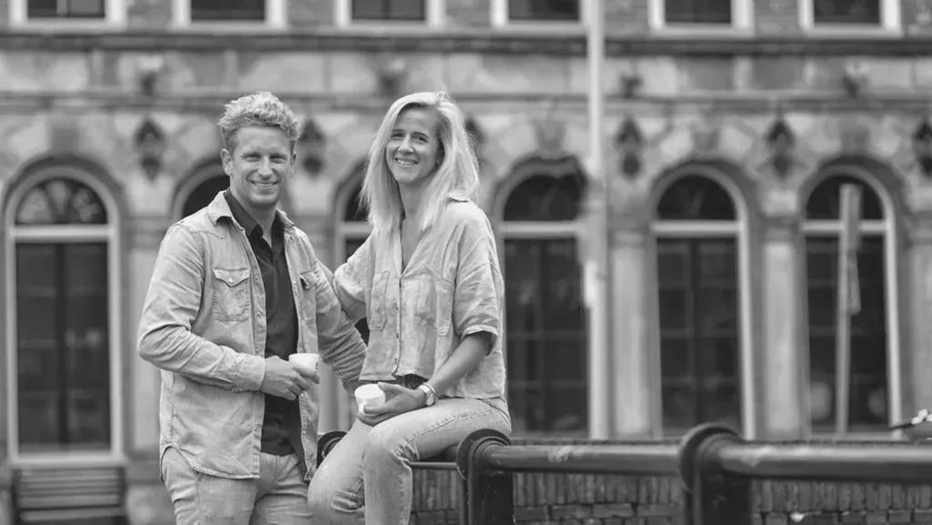 Een man en een vrouw zitten op een bankje voor een gebouw.
