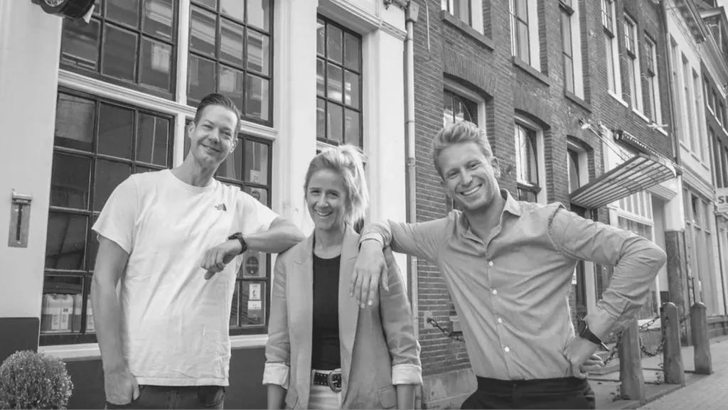 Een groep mensen poseert voor een foto voor een gebouw.