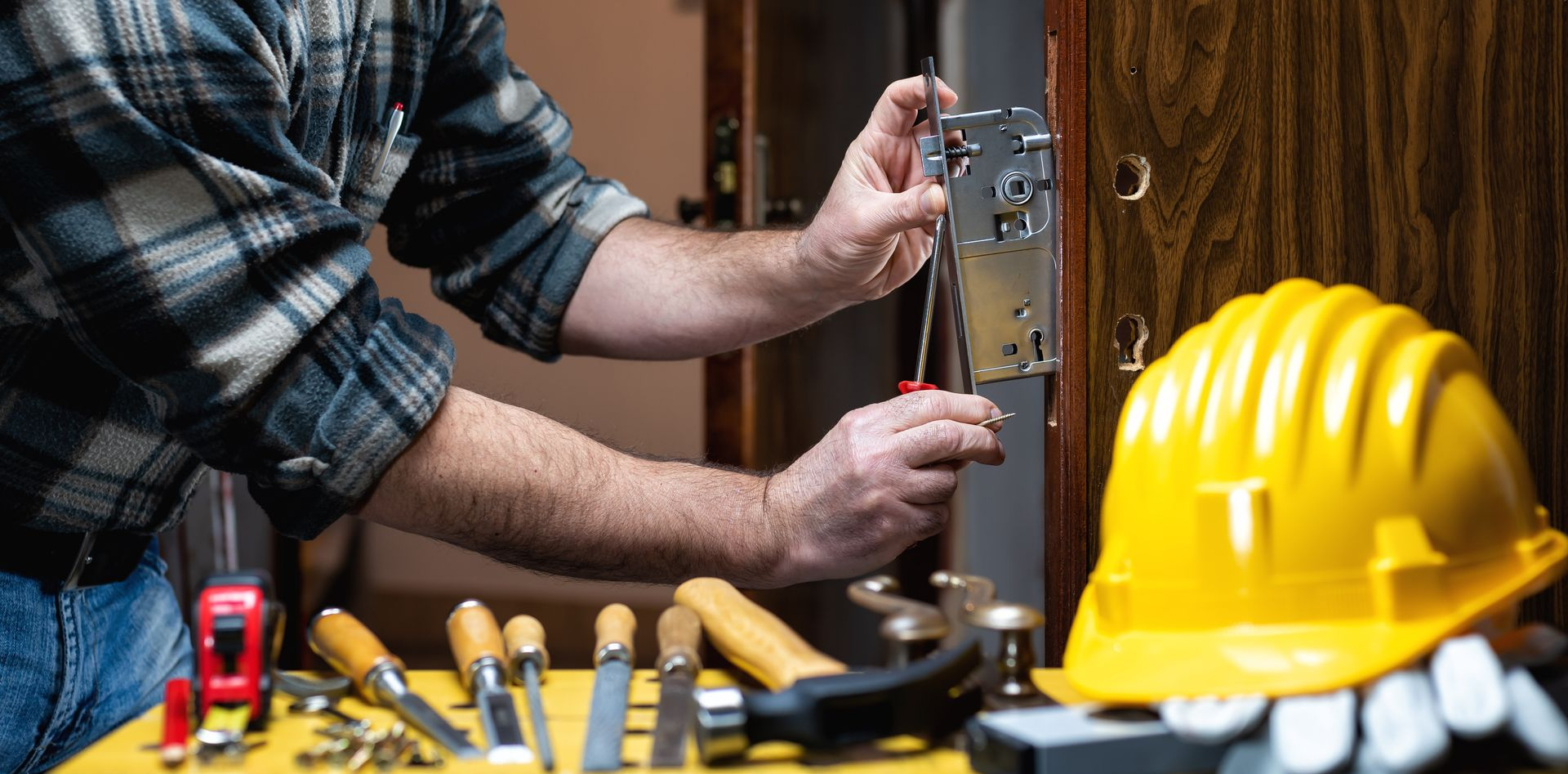 Un serrurier installe une serrure avec des outils.