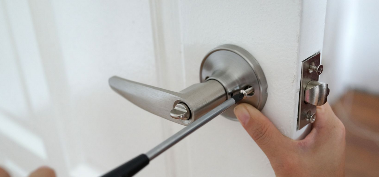 Une personne utilisant un tournevis pour installer une poignée de porte.