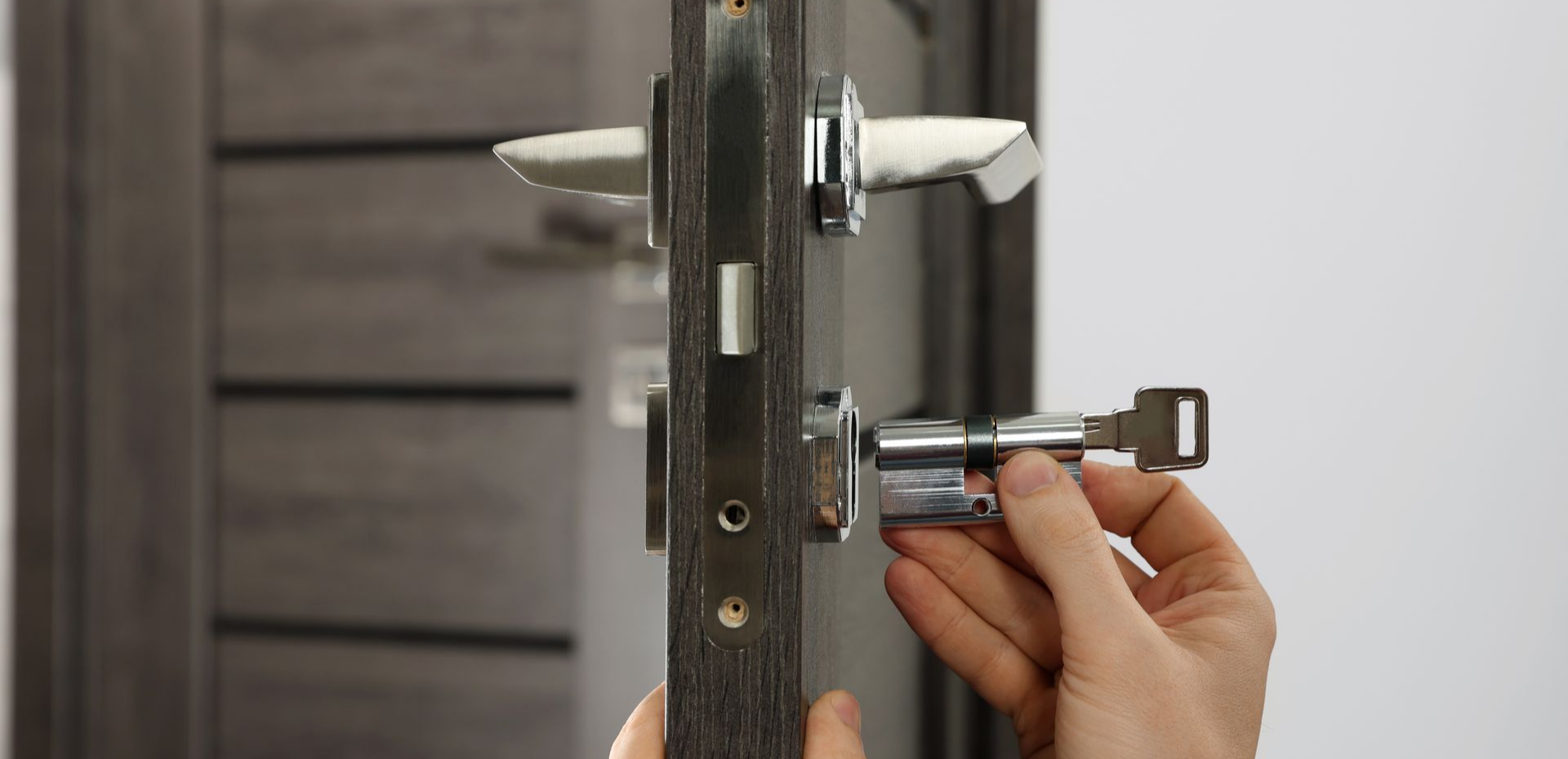Une personne installant une serrure sur une porte grise.