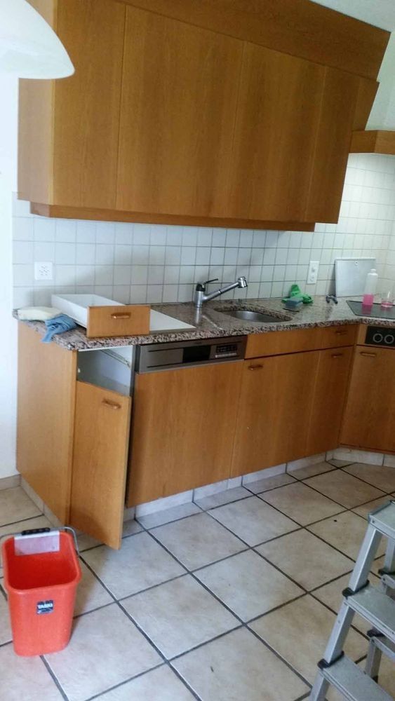 Küche mit Holzschränken, Granitarbeitsplatte, Geschirrspüler und weissem Fliesenspiegel.