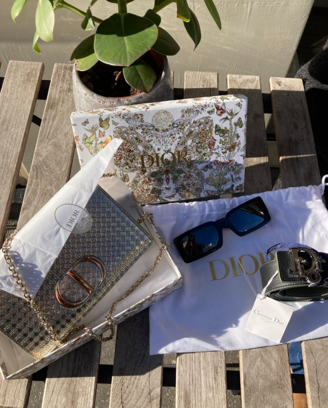 Sac, lunettes de soleil et ceinture Dior posés sur une table basse