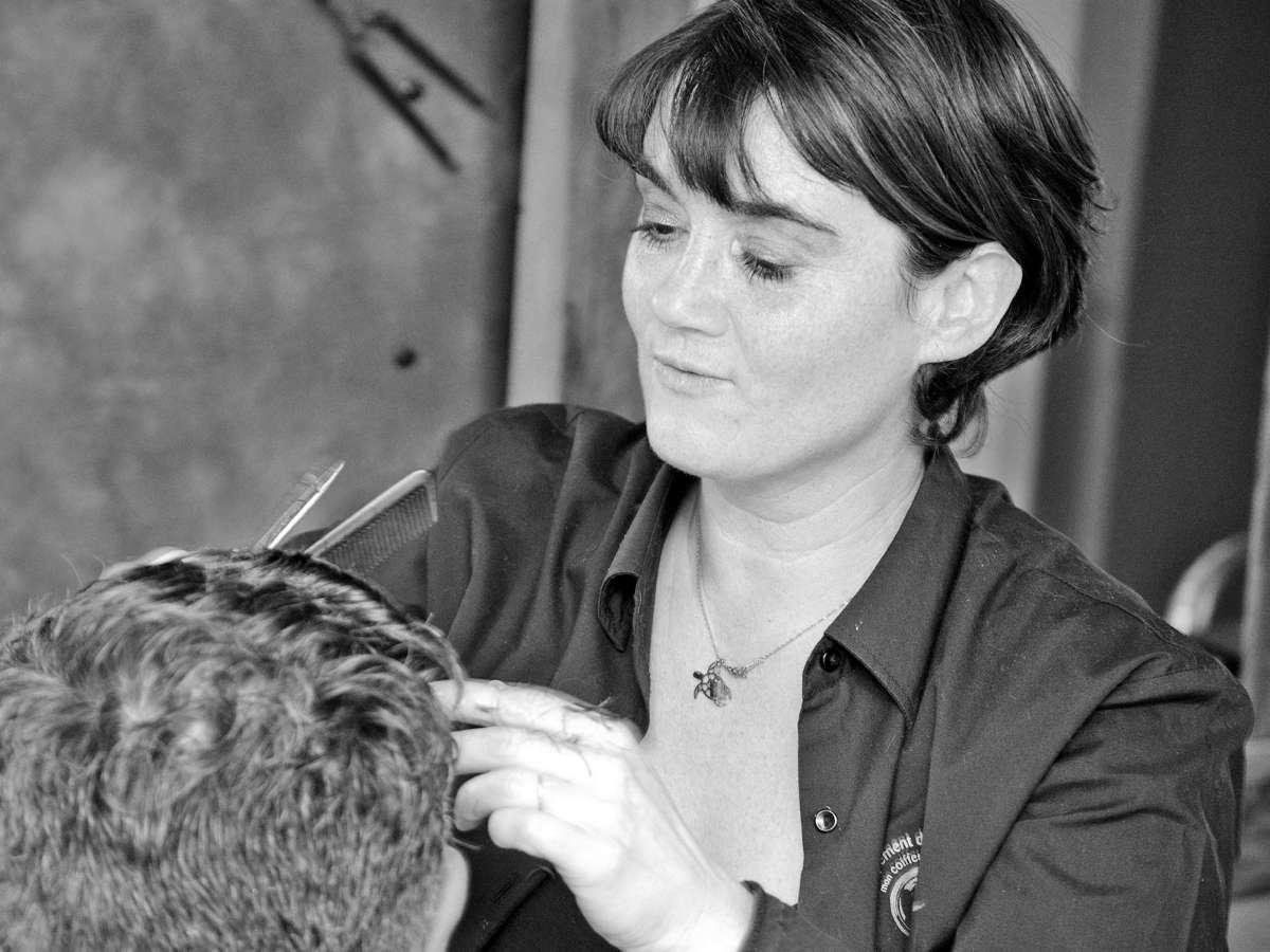 Coiffeuse en train de réaliser une coupe de cheveux