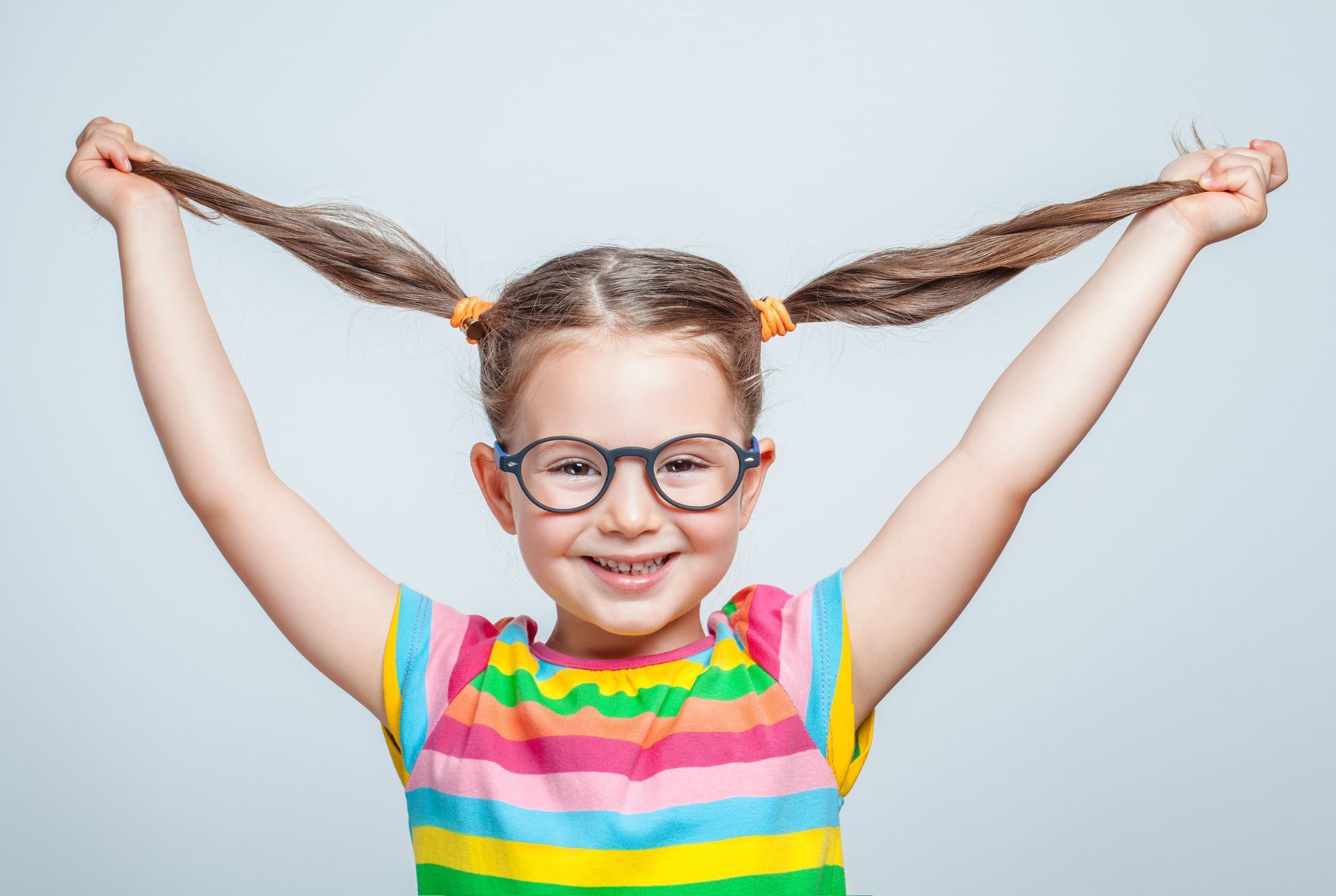 Une petite fille tire sur ses couettes en riant