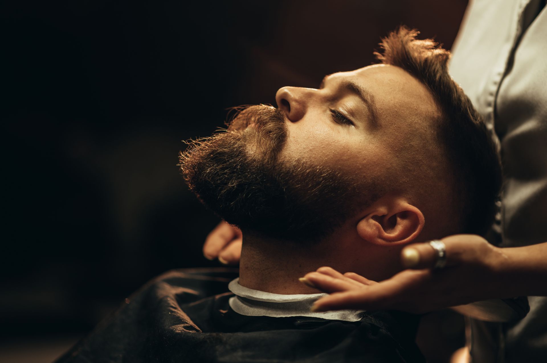 Jeune homme se fait tailler la barbe dans un salon de coiffure