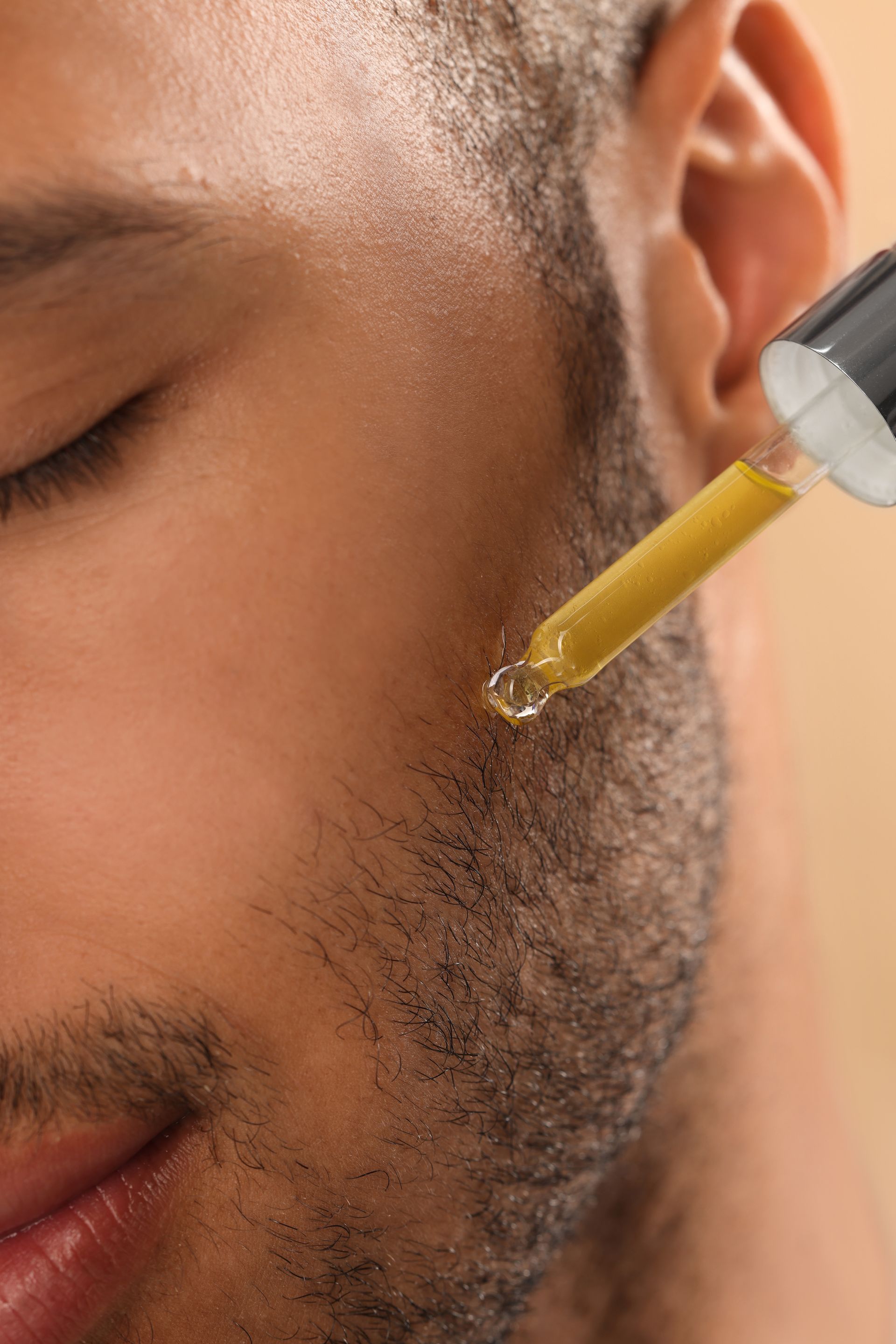 Visage d'homme qui se met des huiles essentielles sur la barbe