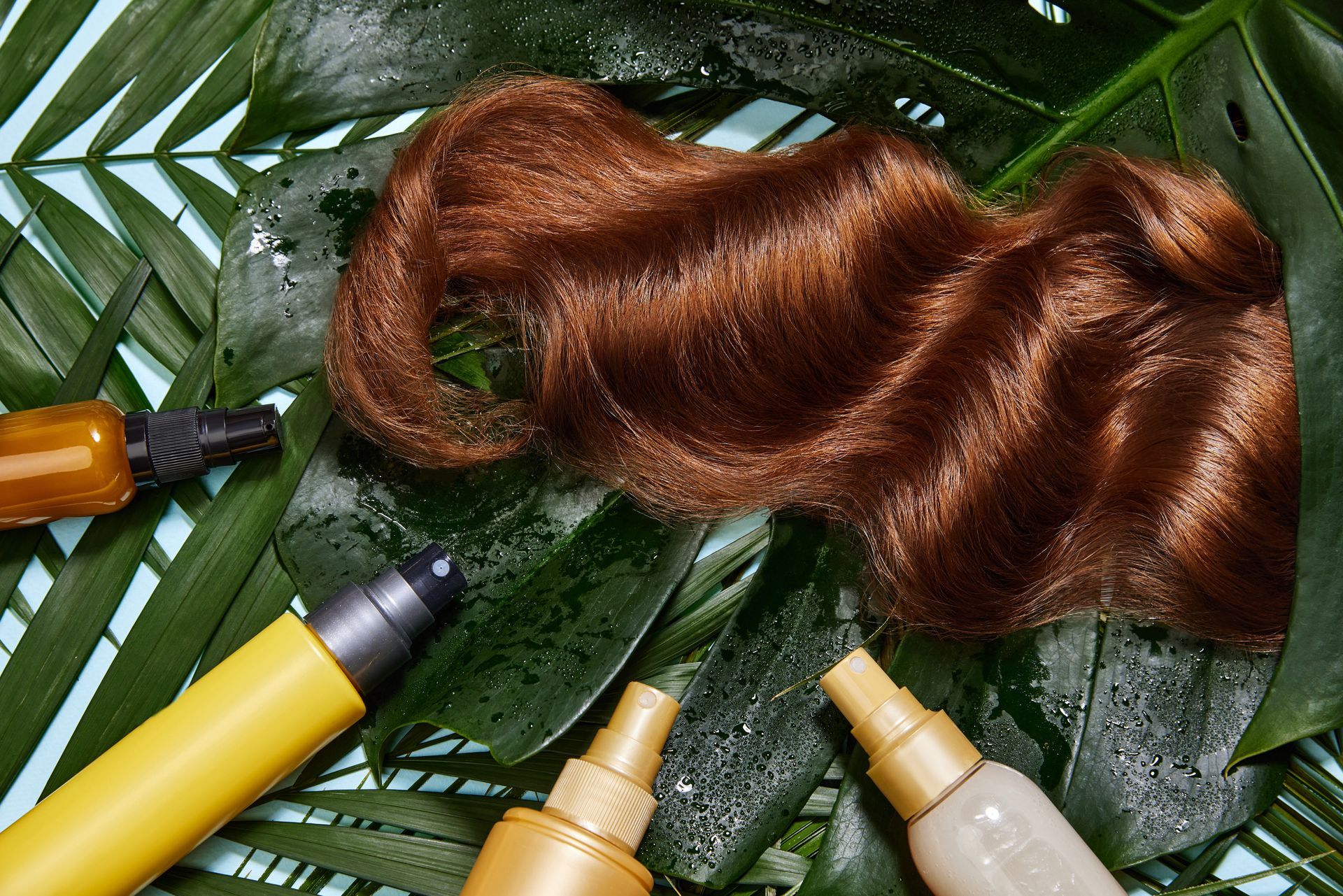 Cheveux roux sur des feuilles, entourés de bouteilles de soins capillaires