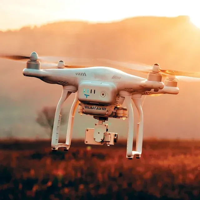 Un dron vuela sobre un campo al atardecer.