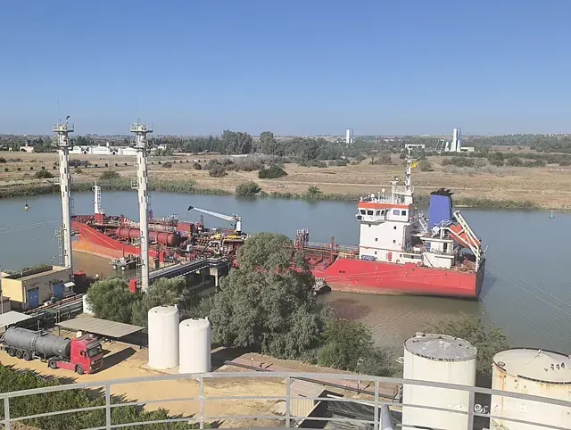 Un gran barco rojo está atracado en medio de un río.