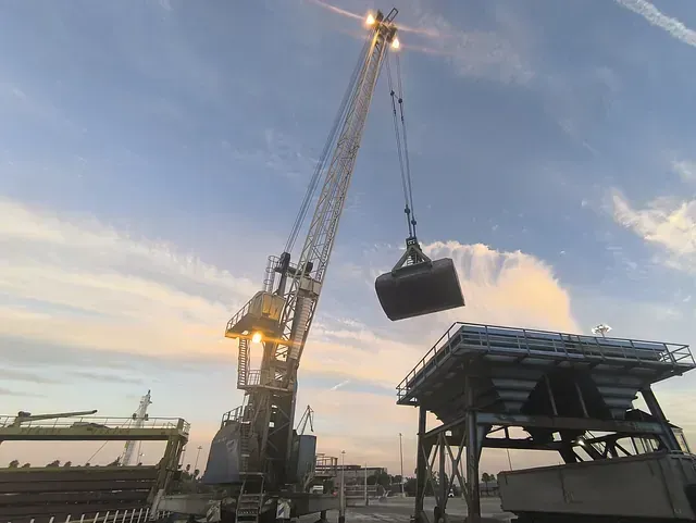 Una gran grúa levanta un gran cubo en el aire.