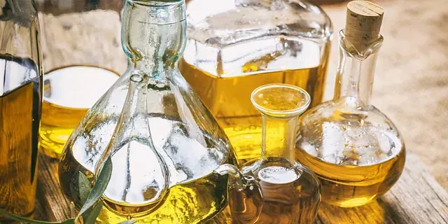 Un grupo de botellas de aceite están sobre una mesa de madera.