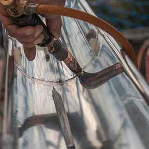 Eine Person schweißt Metallrohre mit einem Schweißbrenner.