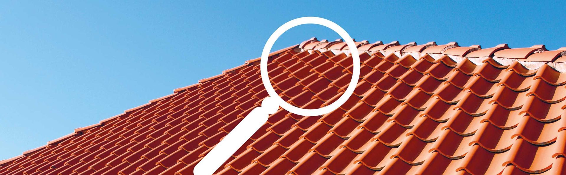 Rotes Ziegeldach vor blauem Himmel.