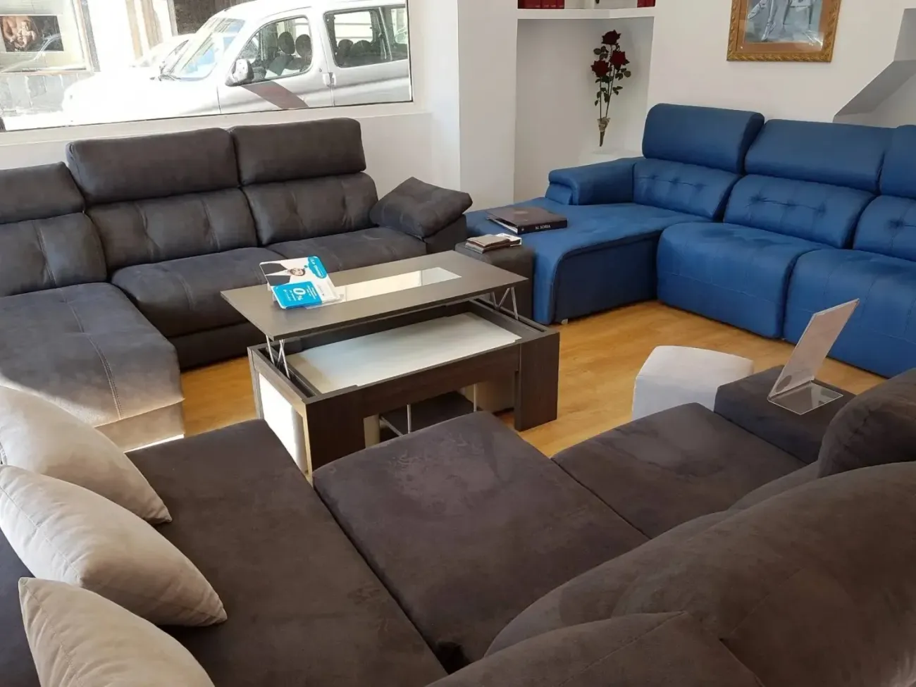 Un escaparate con sofás seccionales de color gris oscuro y azul brillante dispuestos..