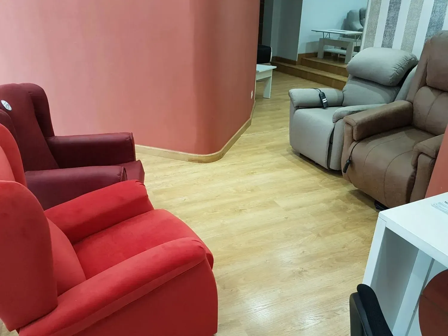 Una exposición en la sala de muestras que presenta varios sillones reclinables en tonos rojos.