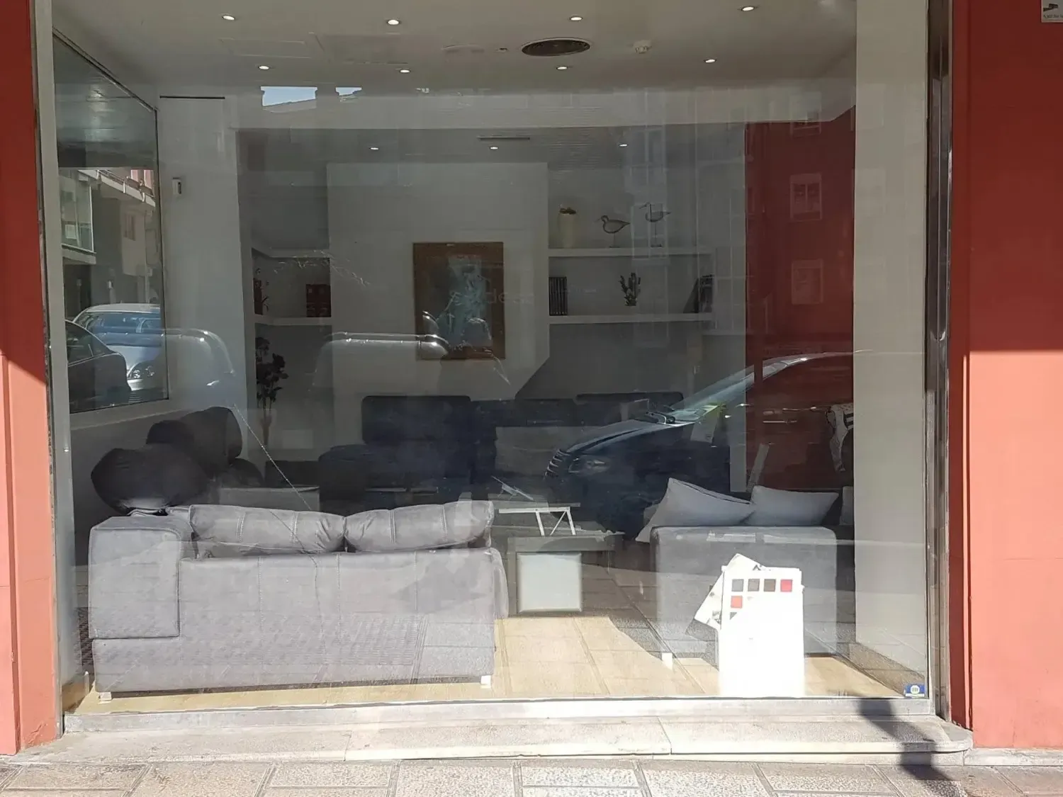 Escaparate que muestra una sala de exposición con sofás gris claro, estanterías modernas.