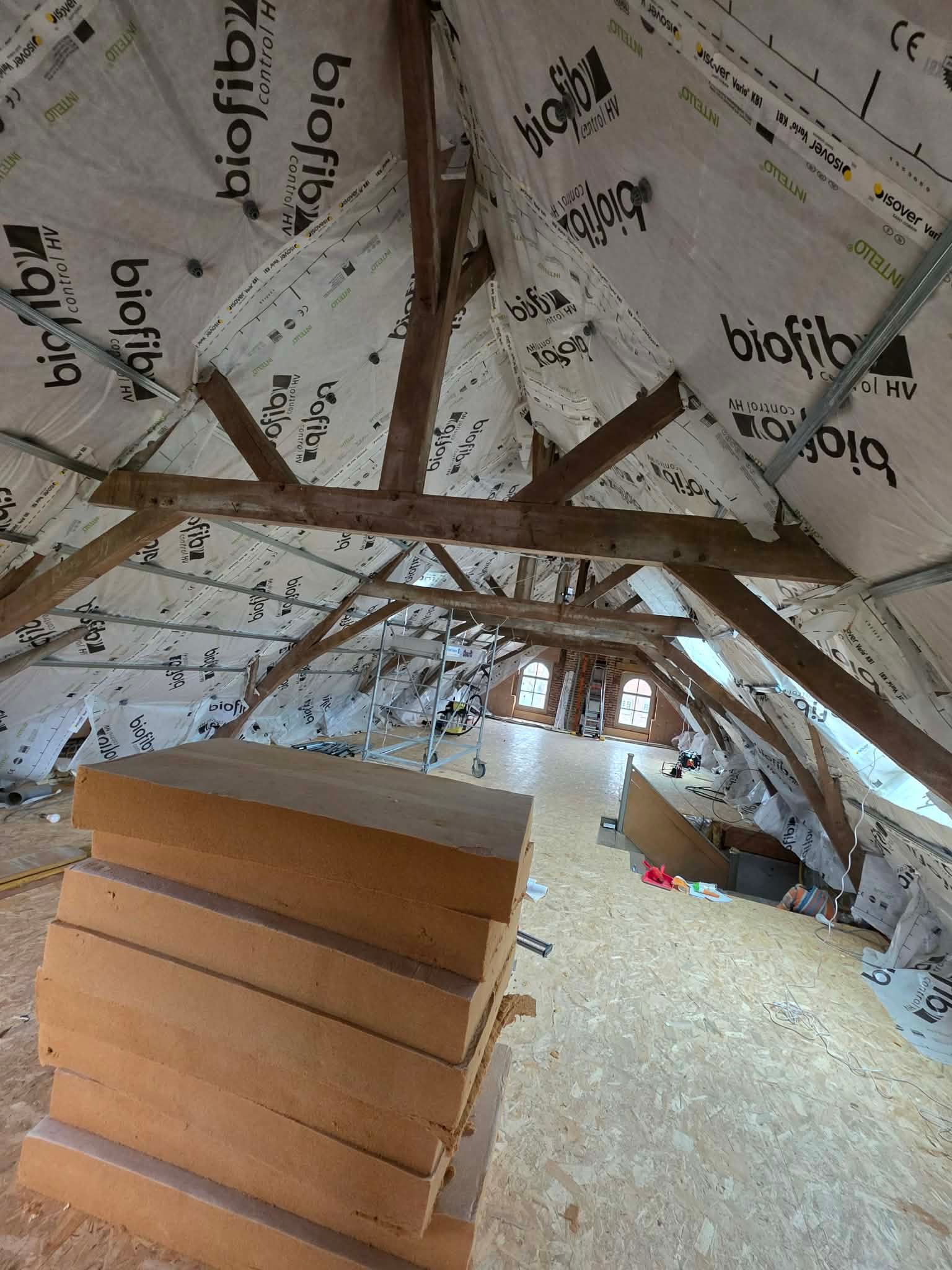 Fermes de toit en bois supportant un toit en tuiles rouges.