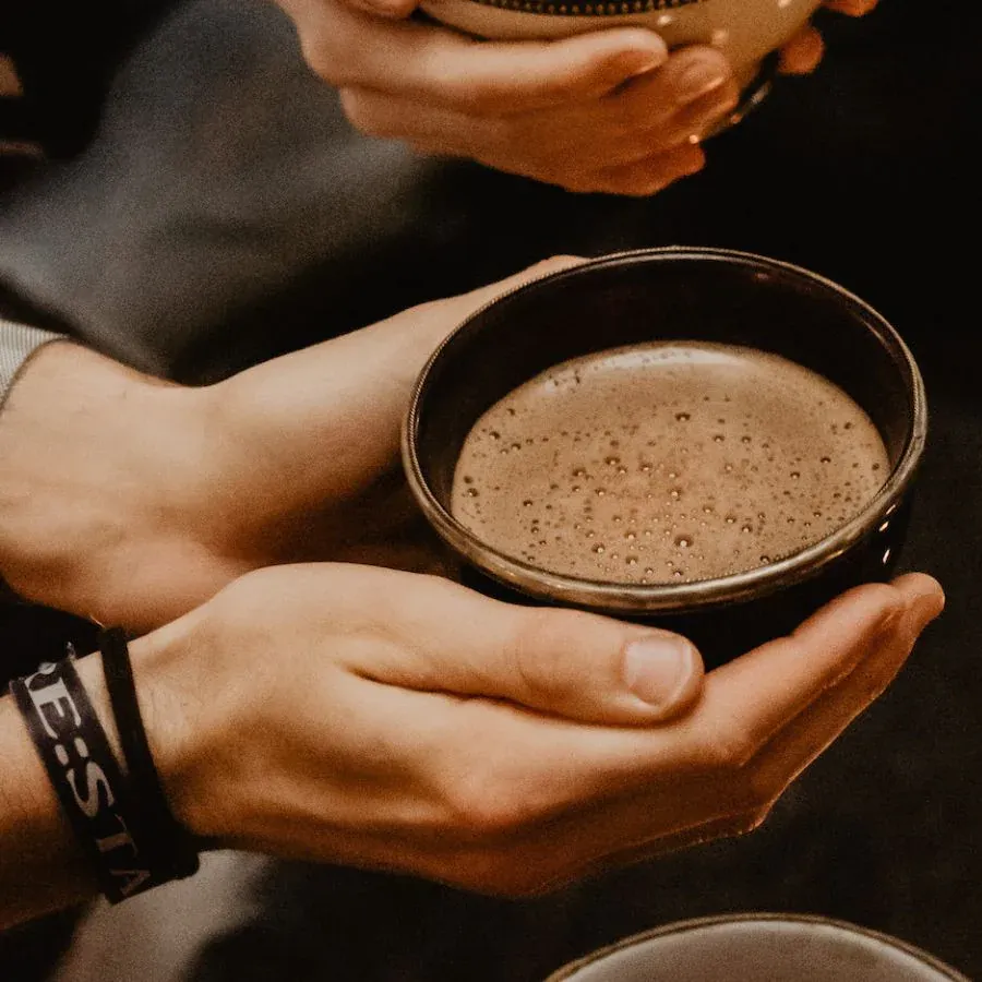Close-up of a glass with a brown drink, rimmed with chili seasoning and a lime slice.