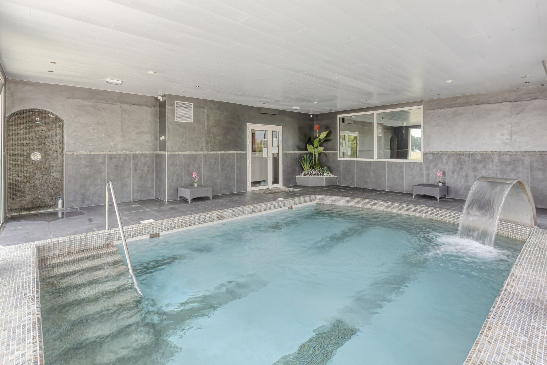 Piscine intérieure avec une cascade et des plantes