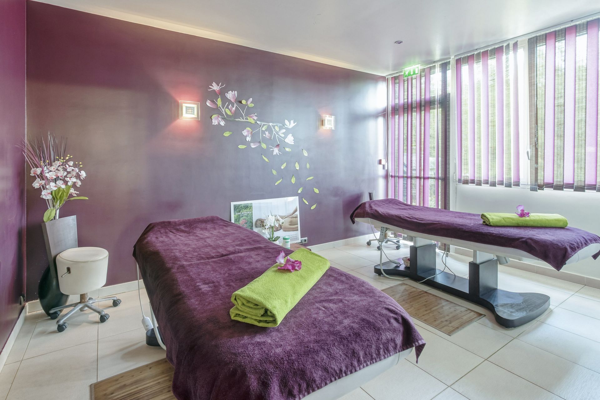 Salle d'un institut de beauté avec deux tables de modelage, des serviettes violettes et vertes