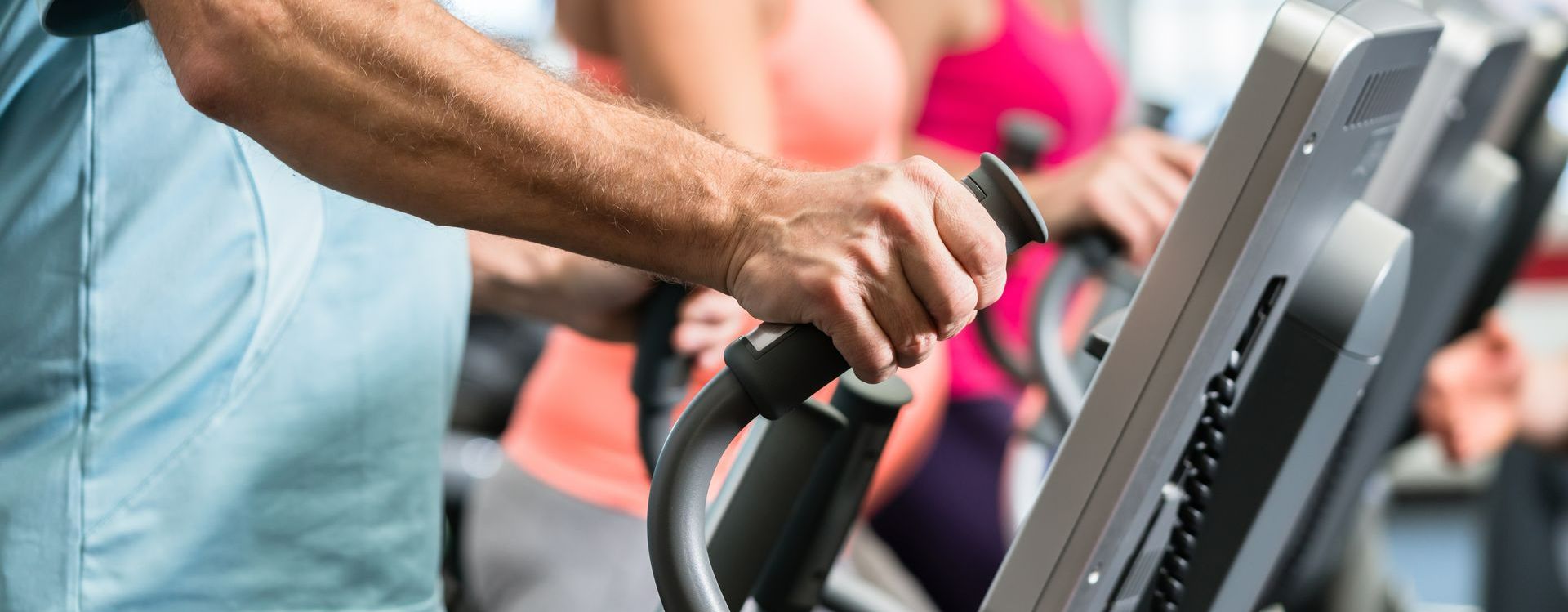 Main qui tient le manche d'une machine de marche active en salle de sport