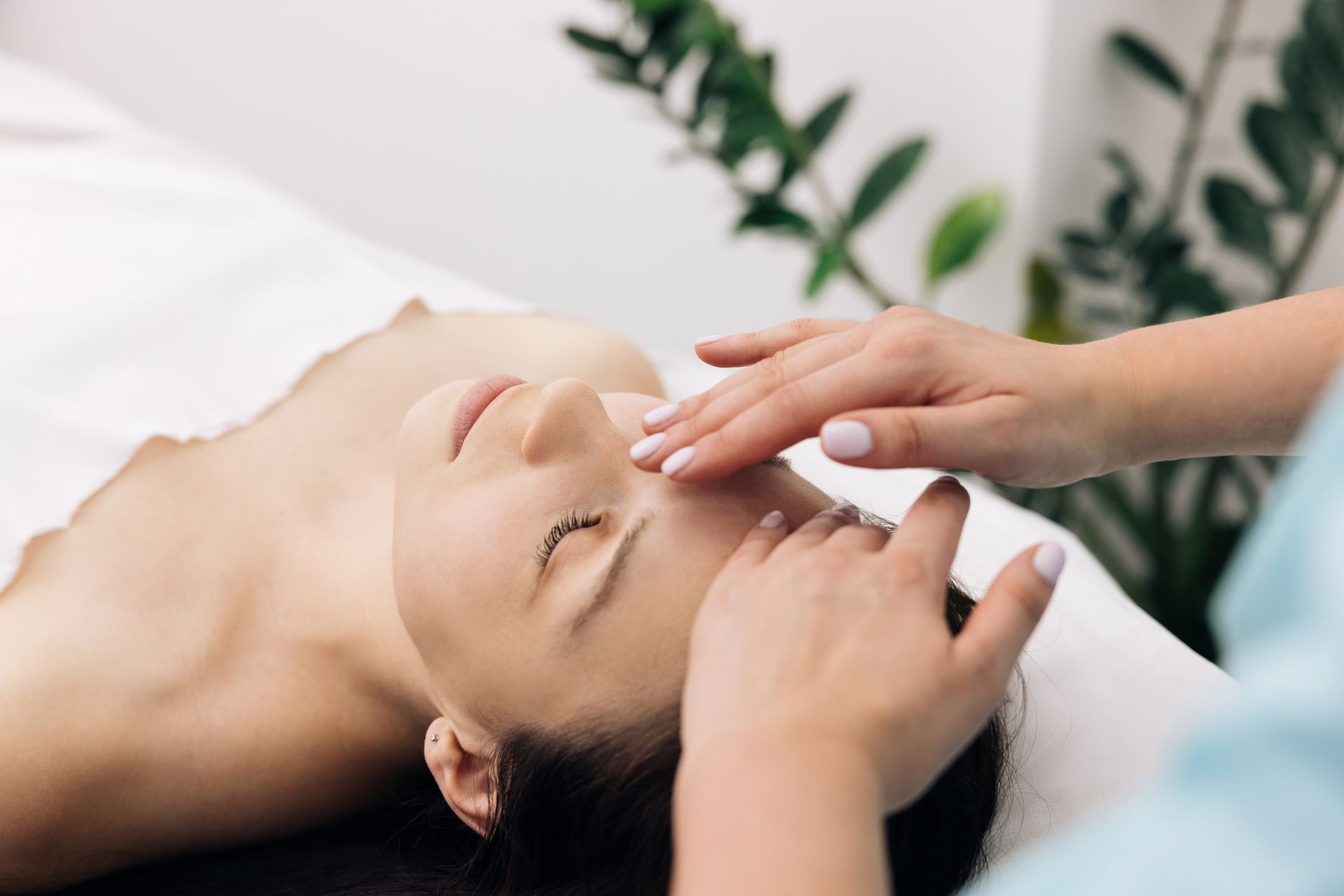 Modelage du visage d'une femme avec une plante dans le fond