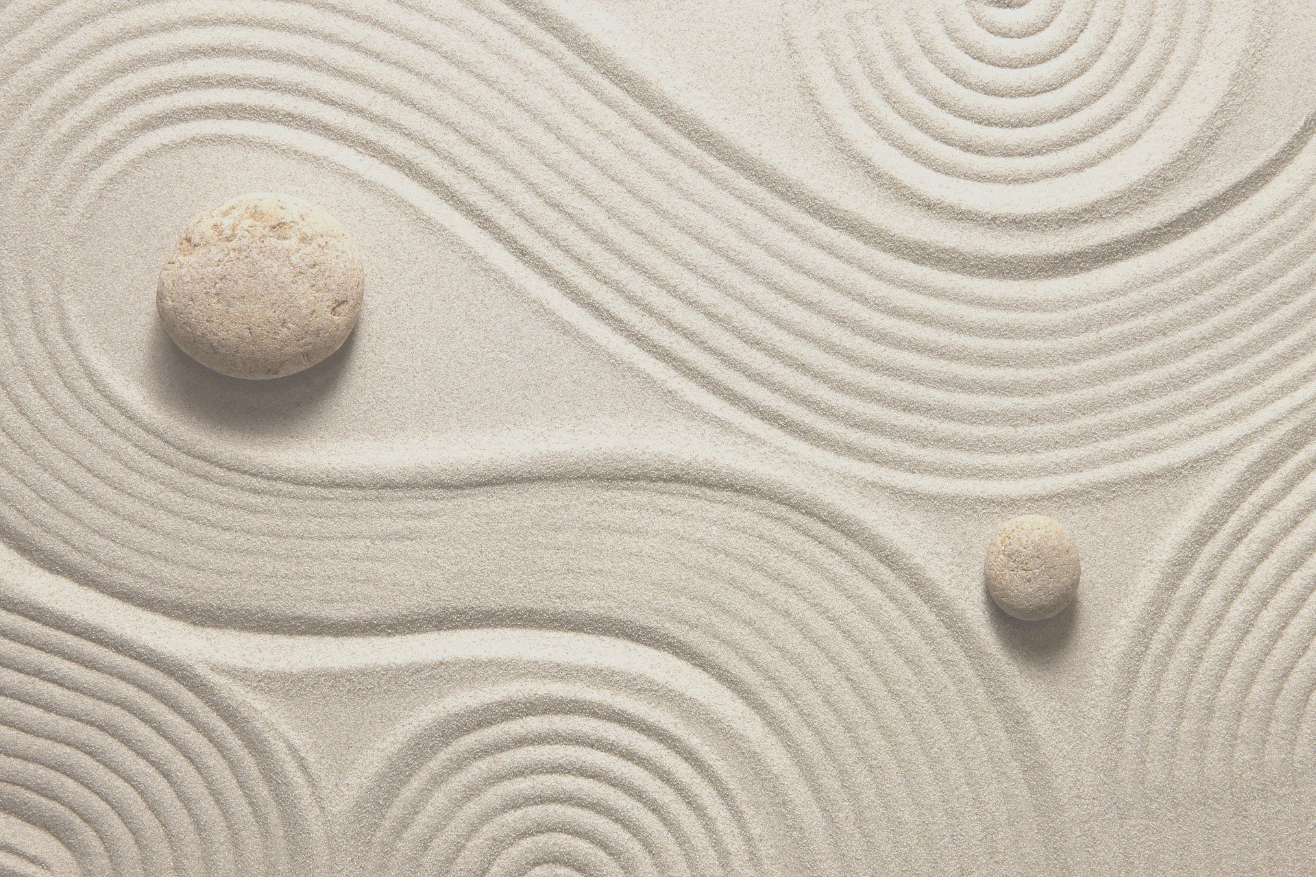 Jardin zen avec deux cailloux et des chemins tracés dans le sable
