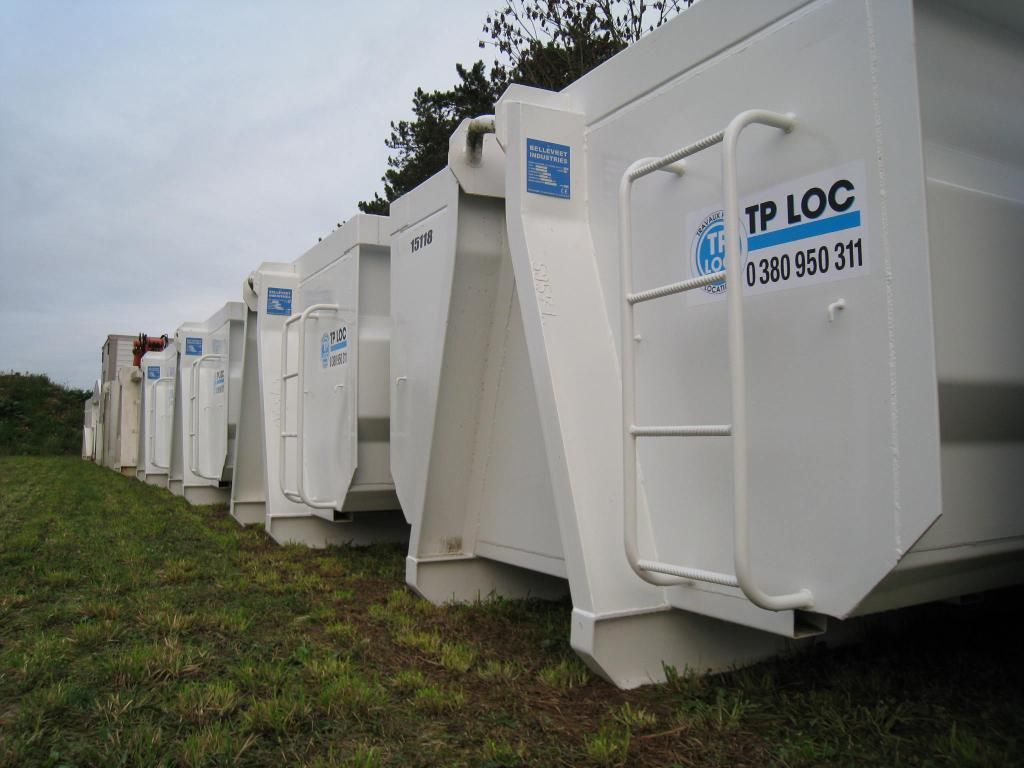 Rangée de toilettes portables blanches sur l'herbe sous un ciel nuageux