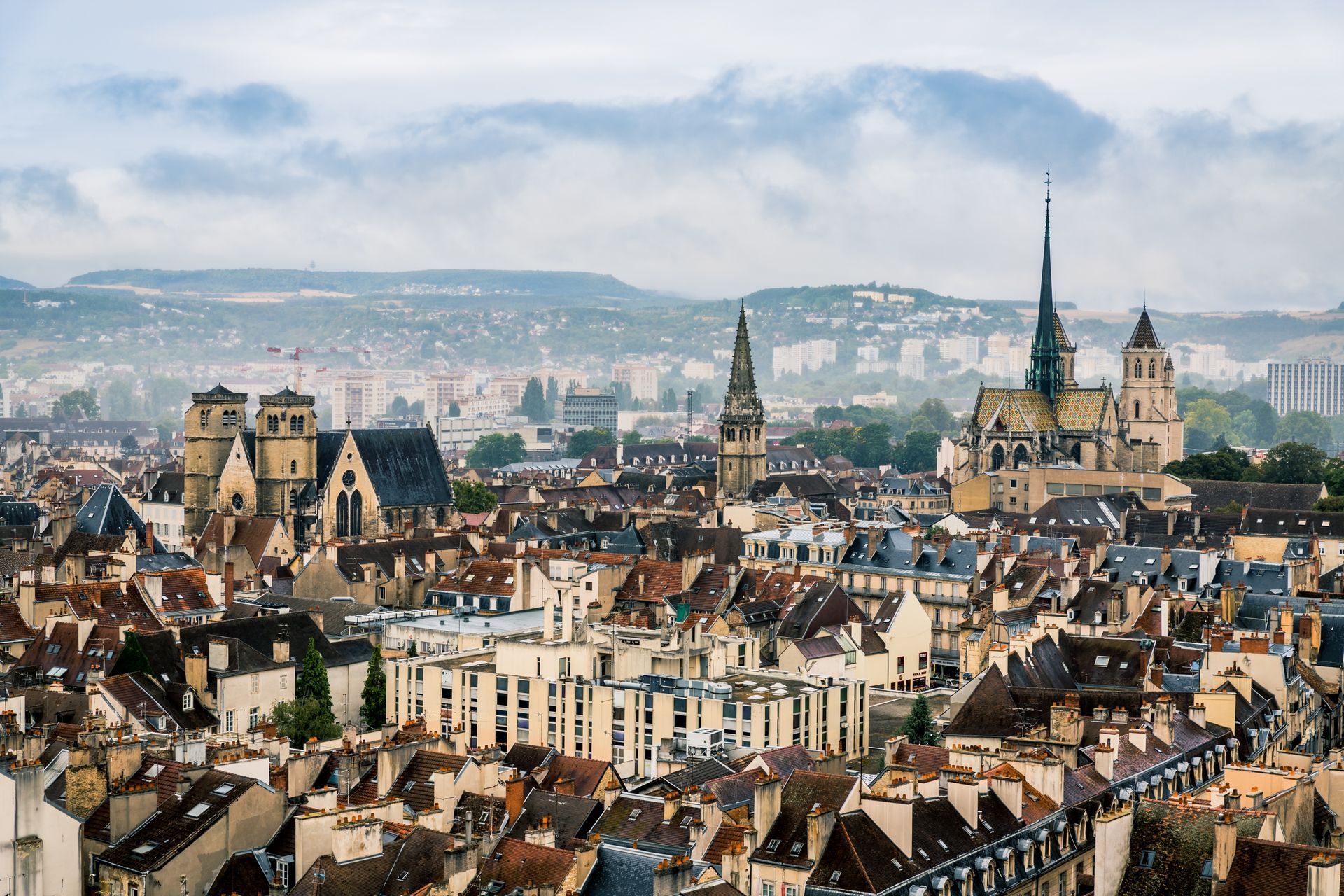 Vue panoramique d'une ville européenne historique aux toits denses et aux clochers d'églises sous un ciel nuageux