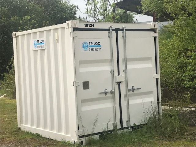 Intérieur d'un conteneur cargo vide avec parois en contreplaqué, plafond en métal et deux armoires bleues au fond.