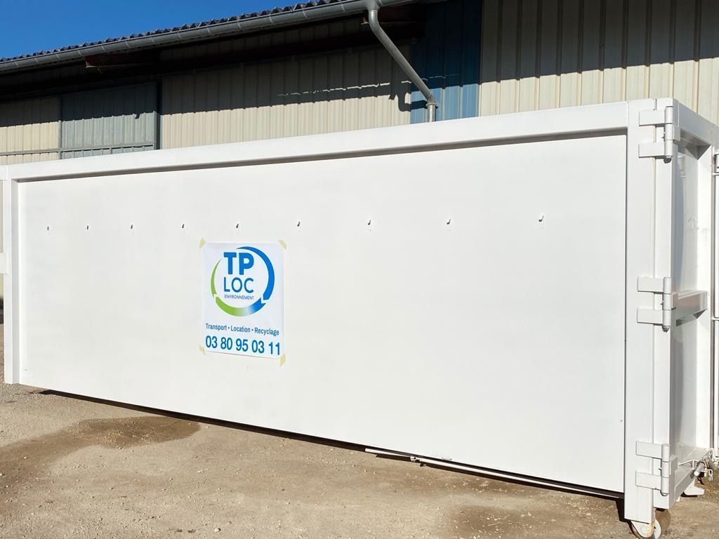 Conteneur de stockage blanc TP Loc Environnement avec logo bleu à côté d'un bâtiment dans une zone industrielle