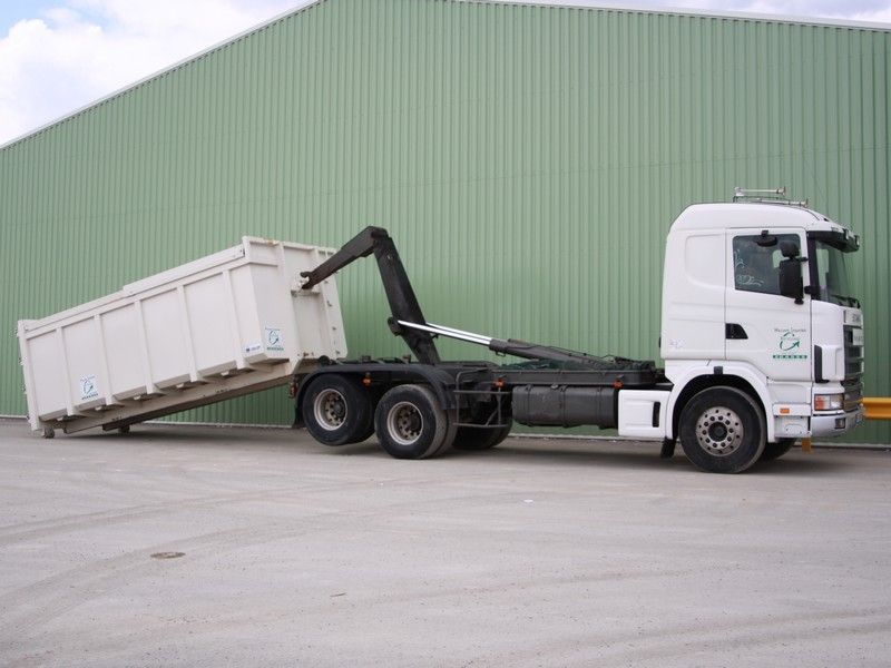 Camion blanc à benne surélevée garé à côté d'un bâtiment industriel vert