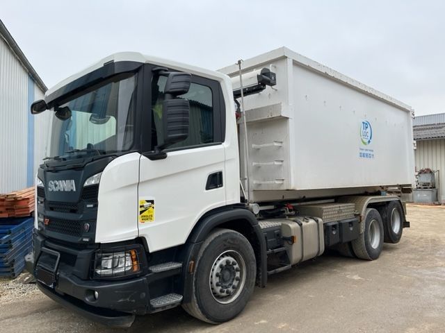 Camion blanc transportant un conteneur noir dans une zone industrielle
