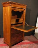 Un bureau en bois avec le couvercle ouvert est posé sur un tapis.