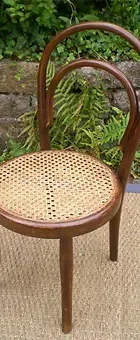 Une chaise en bois avec un siège en osier est posée sur un tapis.