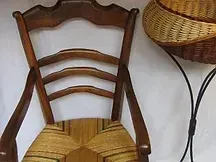 Une chaise en bois est assise à côté d'un panier en osier sur une table.