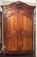 Une grande armoire en bois se trouve dans un couloir à côté d'une porte.
