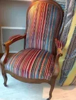 Une chaise avec un siège et un dossier à rayures colorées est posée sur un parquet en bois.