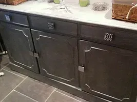 Une vanité de salle de bain avec armoires et tiroirs gris et un lavabo.