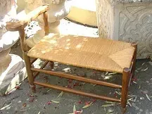 Une chaise en bois avec un siège en osier est posée sur le sol.