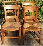 Deux chaises en bois avec des sièges en osier sont assises l'une à côté de l'autre sur le sol.