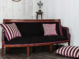 Un canapé noir avec des oreillers rayés roses et blancs dans un salon.