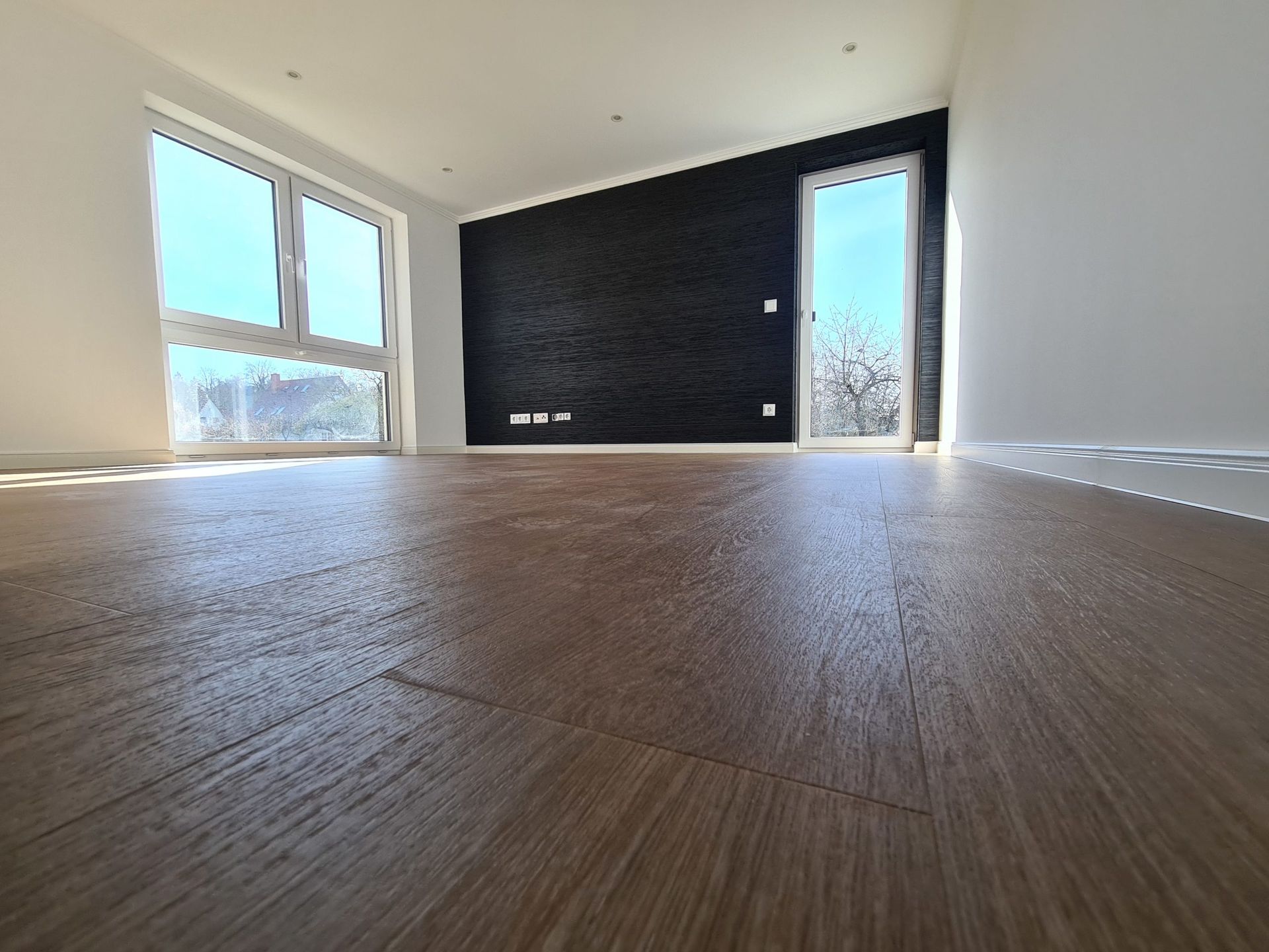 ein leerer Raum mit einem Holzboden und vielen Fenstern