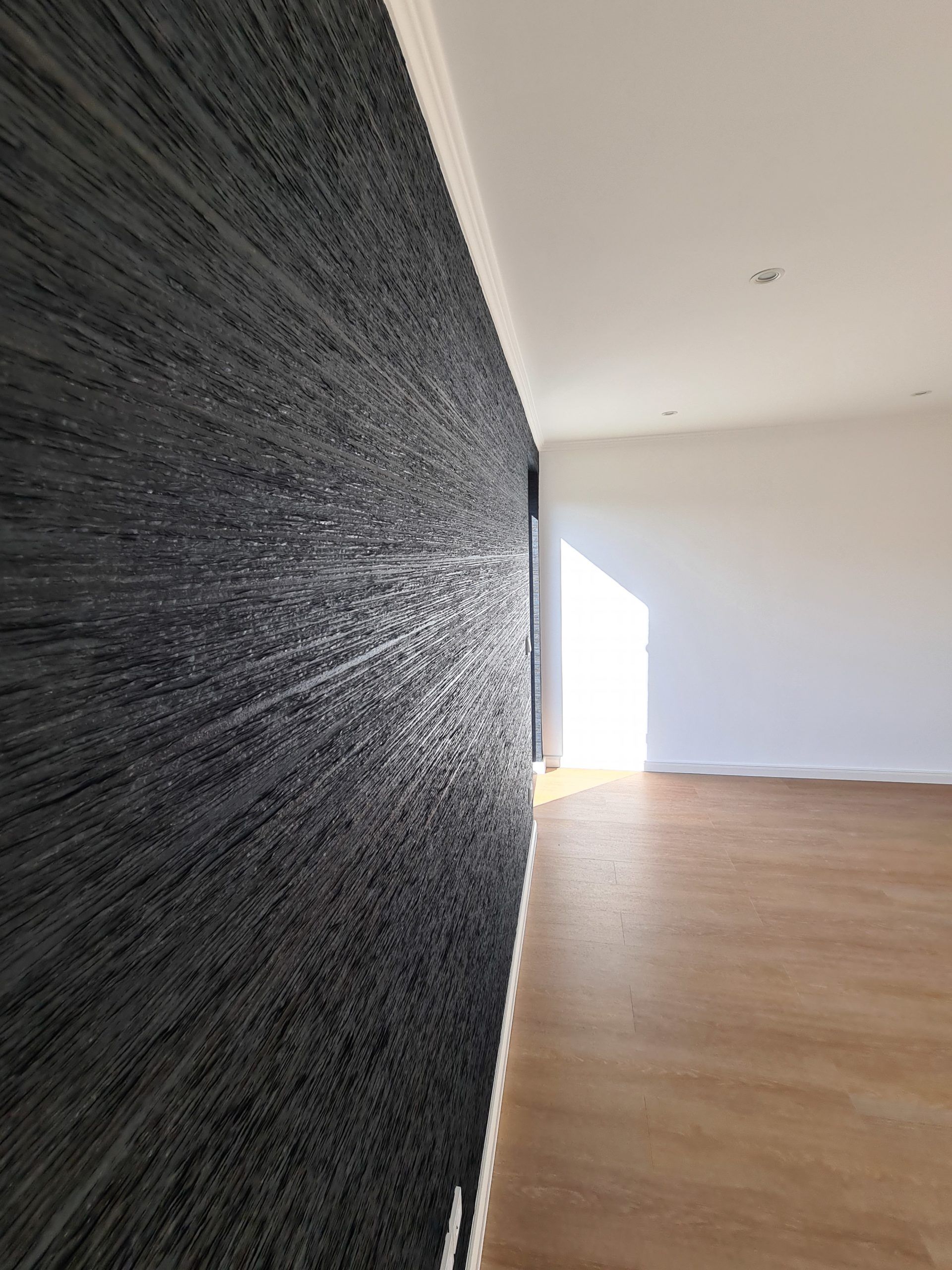 ein leerer Raum mit einer schwarzen Wand und einem Holzboden . Maler Rostock, Malerarbeiten