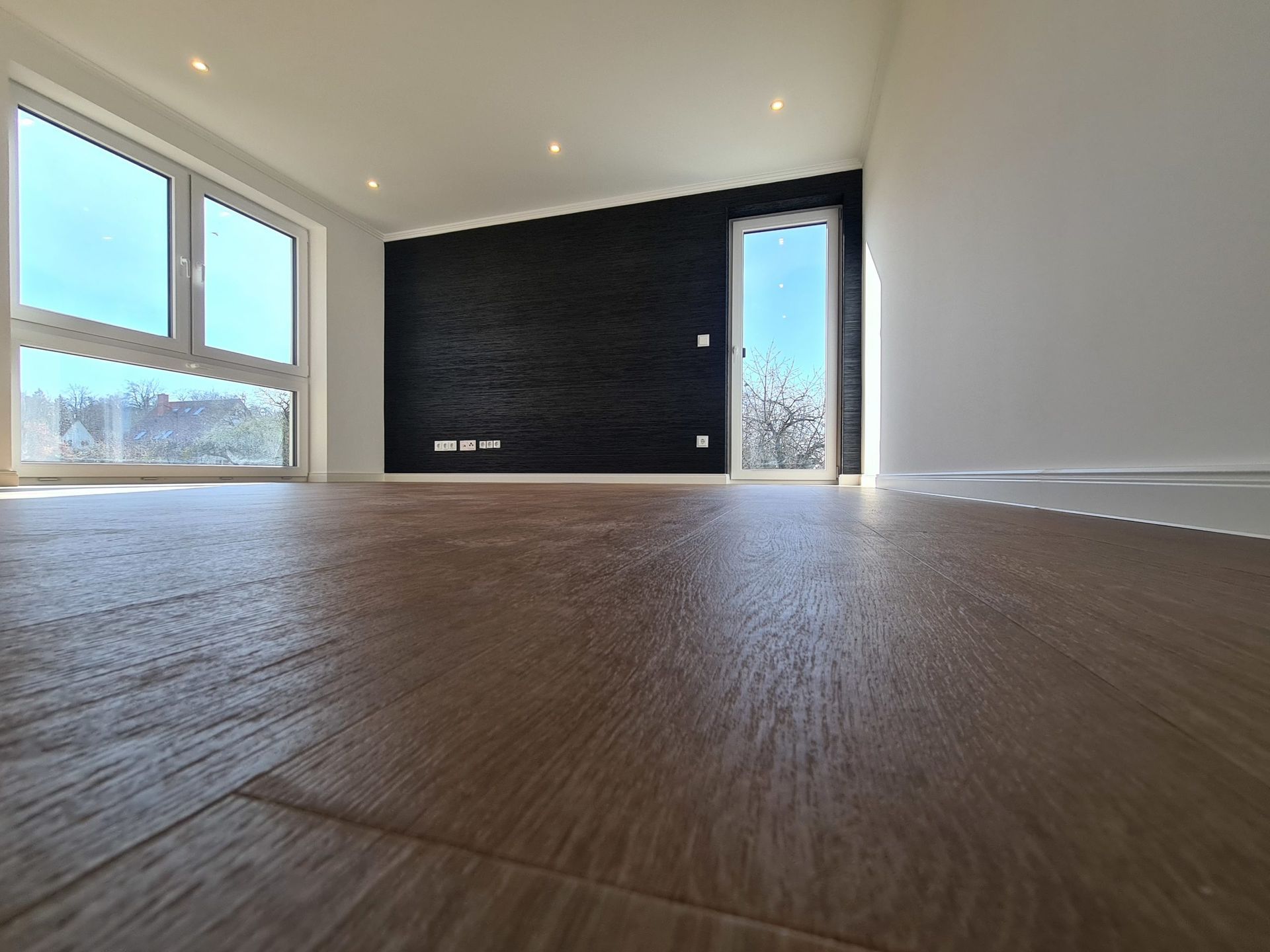 ein leerer Raum mit einer schwarzen Wand und einem Holzboden . Maler Rostock,Malerarbeiten