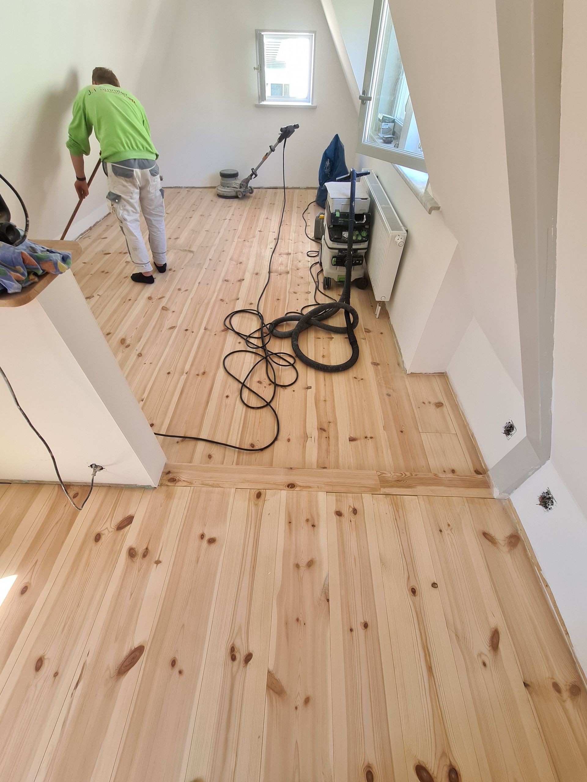 ein leerer Raum mit einem Holzboden und weißen Wänden mit Geselle