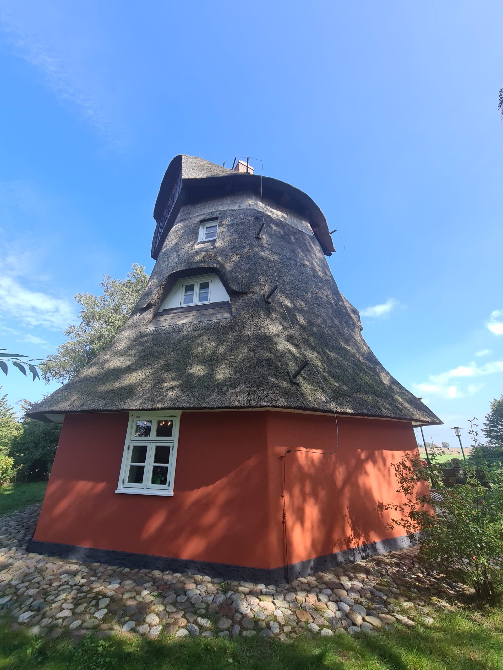 eine rote Windmühle mit Strohdach und einem Fenster .