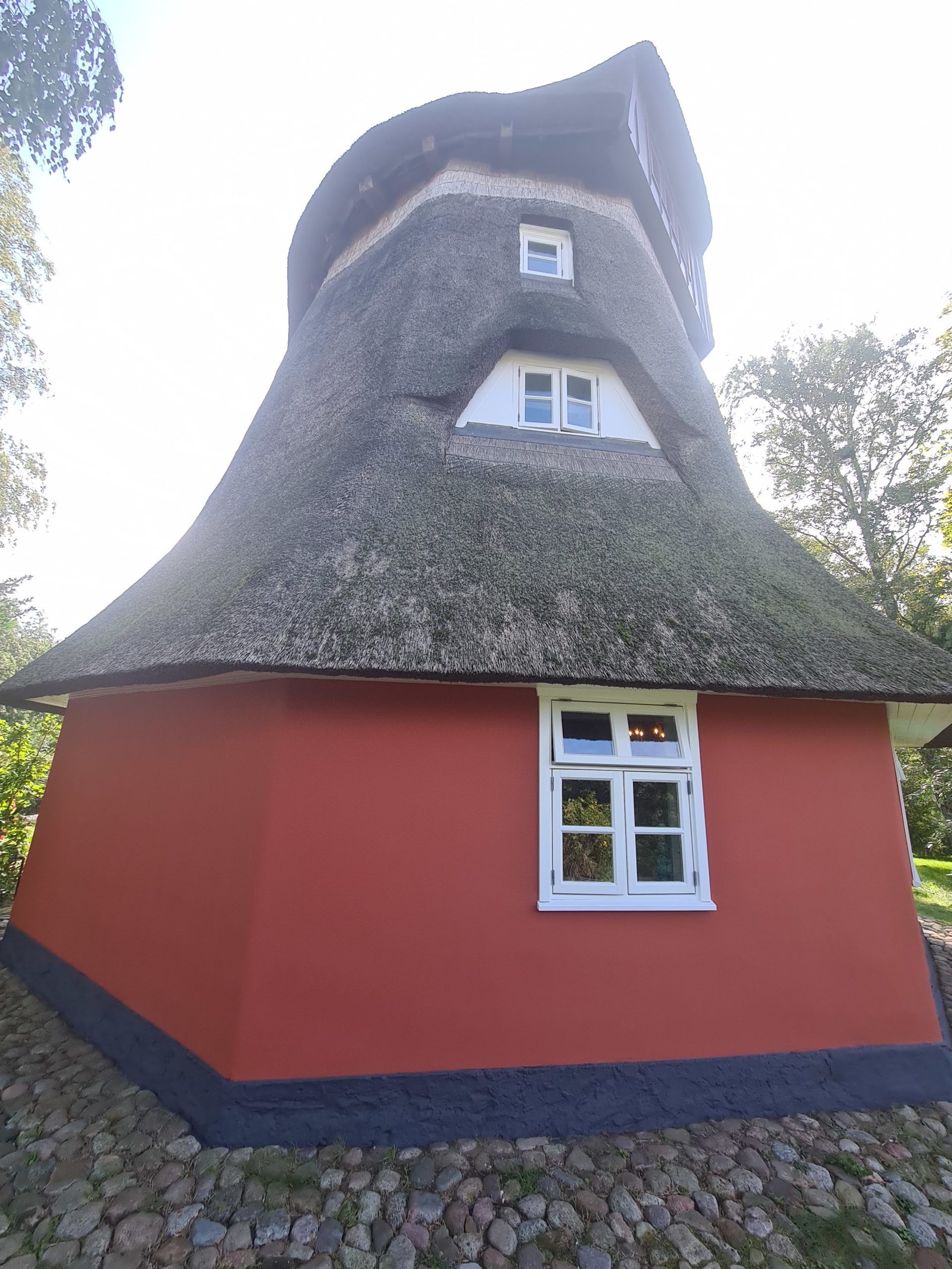 ein rotes Haus mit Strohdach und einem Fenster